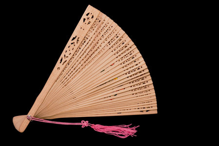 Partially opened bamboo fan with pink tassel, black iso.の写真素材