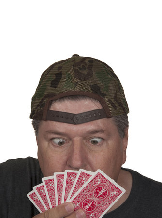 Surprised card player looking at his hand.White isolation.