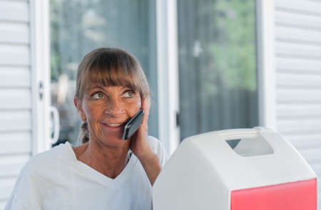 A middle-aged woman gabs on the phone in an outdoor setting の写真素材