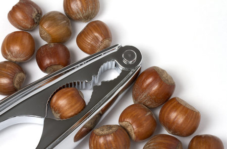 Hazel nuts with chrome nut crackers on white background