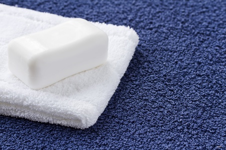 Bar of white soap and washcloth on blue towelの写真素材