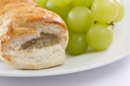Sausage roll and grapes on a plateの写真素材