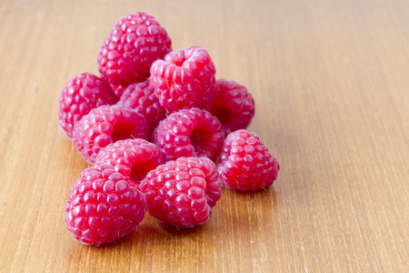 Several red ripe raspberries on wooden table