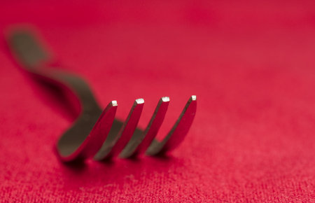 Metal dining fork on red background shallow depth of field