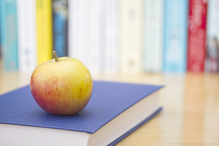 Book with ripe apple a nd row of books in backgroundの写真素材