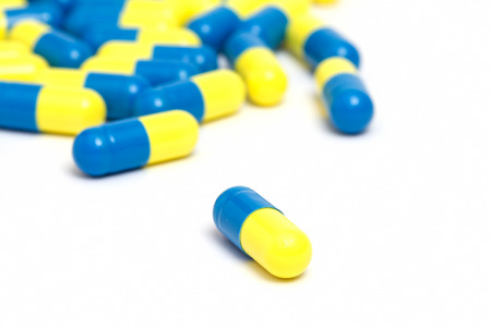Yellow and blue pills on whiteの写真素材