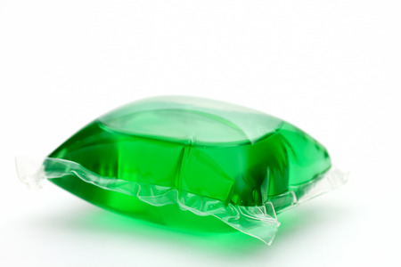 One green laundry detergent capsule on whiteの写真素材