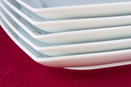 Stack of white square plates on red tableclothの写真素材