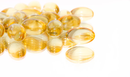 Cod liver oil capsules on a white mirrored background