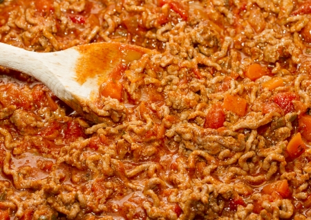 Bolognese sauce cooking in pan with wooden spoonの写真素材