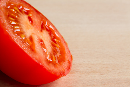 Half of a red ripe tomato on a wooden boardの写真素材