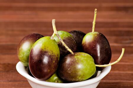 Black/green olives over a wooden tableの写真素材
