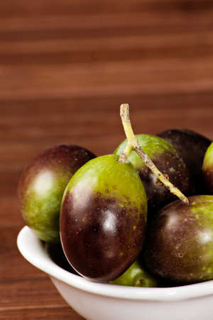Black/green olives over a wooden tableの写真素材