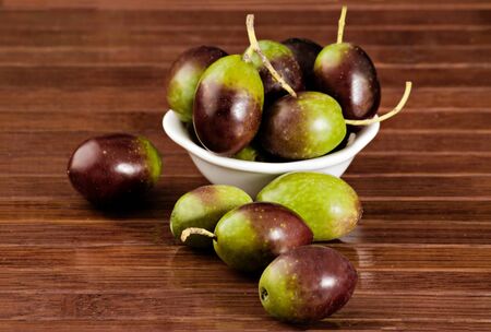 Black/green olives over a wooden tableの写真素材