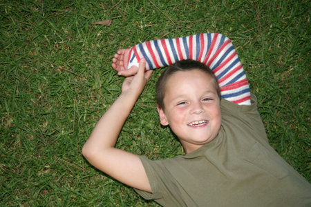 Young boy laying on the grass with a cast on his armの写真素材
