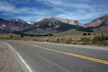 Road leading to snow spotted mountains with blue sky
