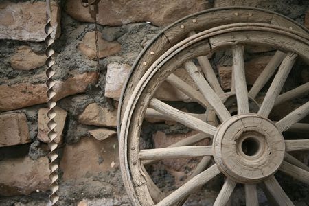 Wagon wheels and a large drill bit against a brick and mortar wall backgroundの写真素材