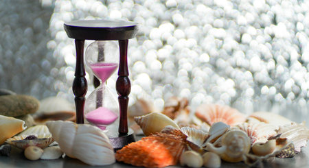 Hourglass and seashells on a silver background. blurred focus.