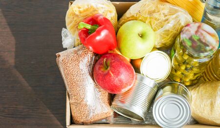 Donation box with various food. Open cardboard box with butter, canned goods, cereals and fruits.の写真素材