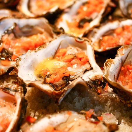 Fresh oysters close-up on a dish, served with oysters, lemon and ice. Healthy seafood. Oyster dinner with champagne in a restaurant. Gourmet foodの写真素材