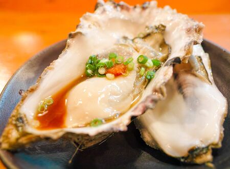 Fresh oysters close-up on a dish, served with oysters, lemon and ice. Healthy seafood. Oyster dinner with champagne in a restaurant. Gourmet foodの写真素材