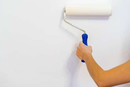 Close-up hands using a paint roller while working indoors.の写真素材