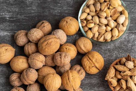 Variety of nuts on a black wood background. walnuts, hazelnuts, pistachios. Top view ingredients. Banner.の写真素材