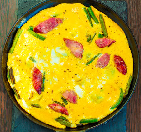 scrambled eggs with sausage and herbs in a pan.の写真素材