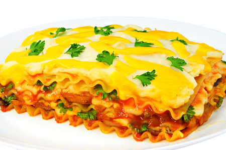 Delicious lasagna slice on a plate, isolated on white backgroundの写真素材