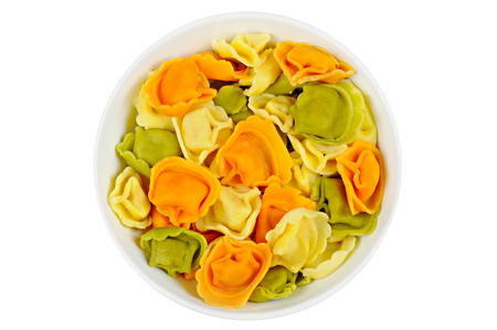 Raw colored tortellini in a bowl, on a white backgroundの写真素材