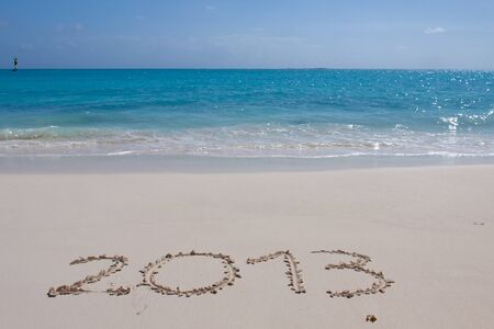 Year 2013 hand written on the white sand in front of the seaの写真素材
