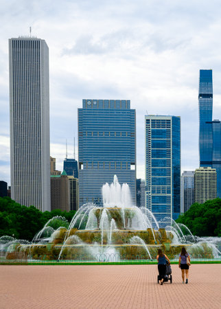 Two people walking in front of Buckingham Foundation with the Chicago skylineのeditorial素材