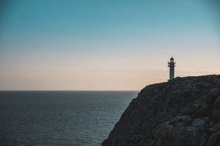 Lighthouse on a cliff on a sunset in Formenteraの写真素材