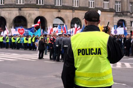 Police officer talking on a radio protecting an anti-government demonstration in Warsaw Poland on 7 October 2006 (Blue March by Platforma Obywatelska). Purposely taken with a shallow DOF not to detail faces.の写真素材