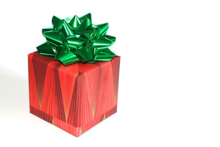 Wrapped Christmas present in a box with a green bow ribbon on top isolated on white with some space for your ad on the rightの写真素材