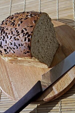 Whole grain bread on a wooden cutting board: healthy nutrition conceptの写真素材