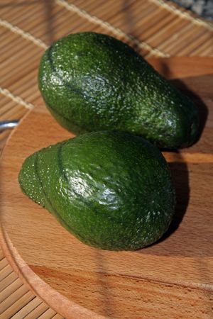 Two avocados on a wooden cutting board: nutrition conceptの写真素材