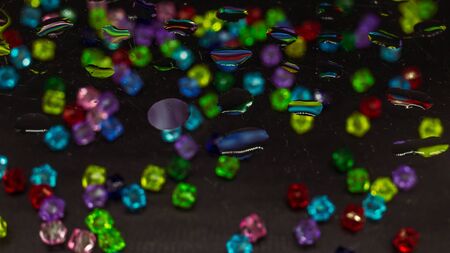 Colorful small beads behind glass, water dropsの写真素材