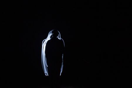 Flashlight in the dark, light painted people silhouetteの写真素材