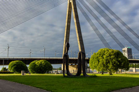 Riga, Latvia- June 29, 2019: metal art work people sculpture, capital city bridge backgroundのeditorial素材