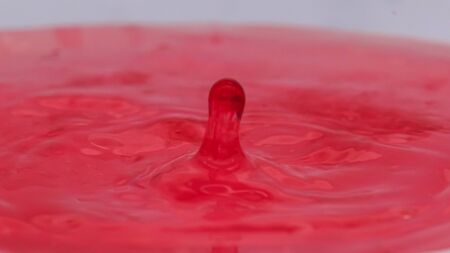 Pink color drop falling and splashing in water, creative forms freezingの写真素材