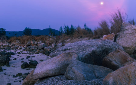 Thailand island full moon at sunset time, rocks foreground