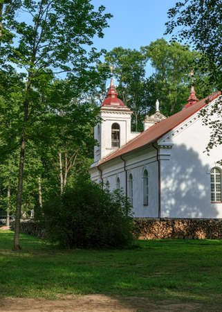Kurmene, Latvia - June 28, 2020: Kurmene Roman Catholic Church,  was built in 1870 and is decorated by a sculpture of St.Peter. The manor park is arranged as a landscape  with individual elements  and 19th century artificial castle ruins with an open-air のeditorial素材
