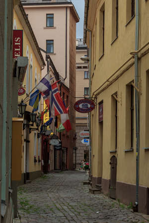 Riga, Latvia- June 29 2020: old city tiny pavement walking street, country flagsのeditorial素材