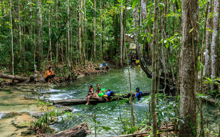 Krabi town, Thailand- March 28 2019: Emerald pool first level wterfall near entrance, citizen enjoy, water washed tree rootのeditorial素材