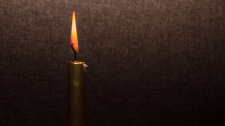 Gold color shiny candle fire and orange flame, on brown backgroundの写真素材