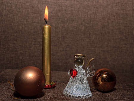 Glass angel with red heart Christmas decoration, gold color ball and shiny candle. Christmas gift card concept on brown backgroundの写真素材
