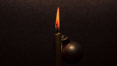 Gold color shiny candle fire and orange flame, decoration ball, on brown background. Creative christmas tree.の写真素材