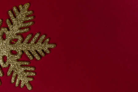 Gold color shiny snowflake decoration in corner on red background, Christmas gift card frameの写真素材