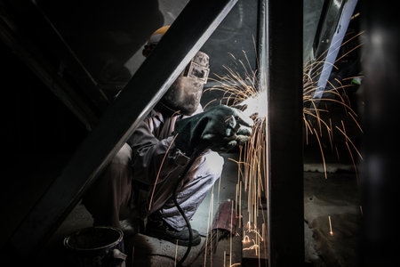 Industrial factory worker working welding metal with sparks